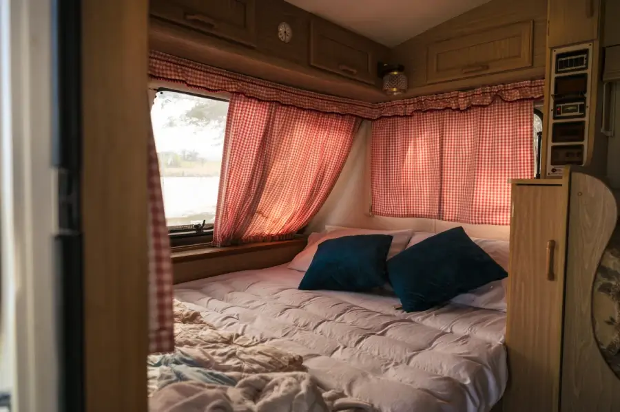 A cozy RV bed with a small window and nice view