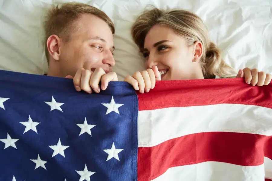Cute young couple on a new bed under american flag