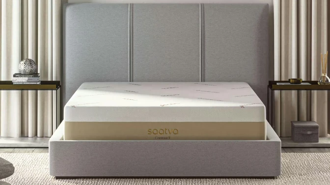 The Saatva Contour5 memory foam mattress displayed in a modern bedroom setting with a gray upholstered headboard, featured as a top luxury alternative to Tempur-Pedic.