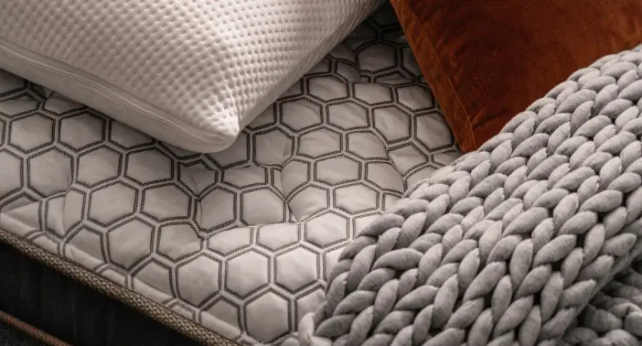 close up image of titan plus elite mattress with knitted blanket and pillows