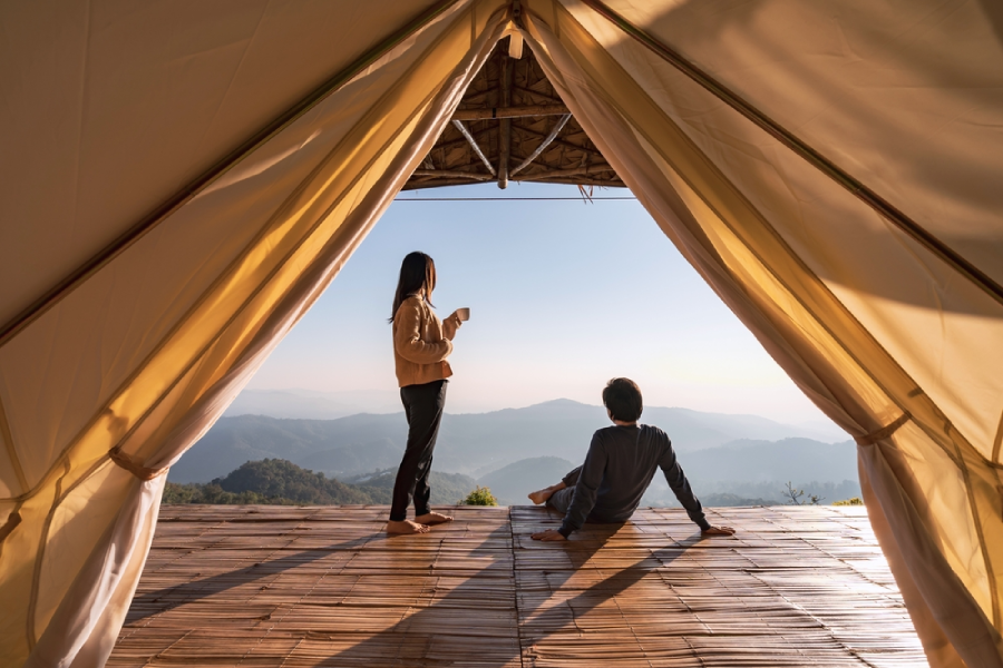 couple standing outside tent with view of mountains