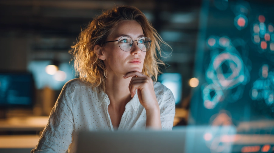A young entrepreneur wearing glasses sits at a desk with futuristic digital interfaces glowing in front of her, symbolizing the choice between fast time-to-MVP and scalable AI app solutions.