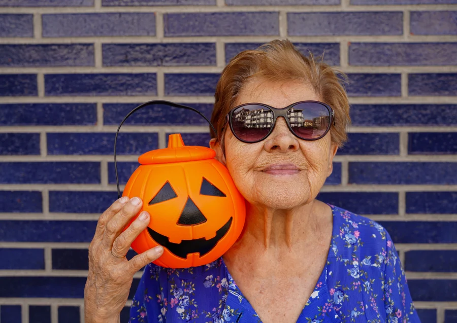 Elderly lady with getting ready for Holloween with pumpkin bucket and cool sunglasses